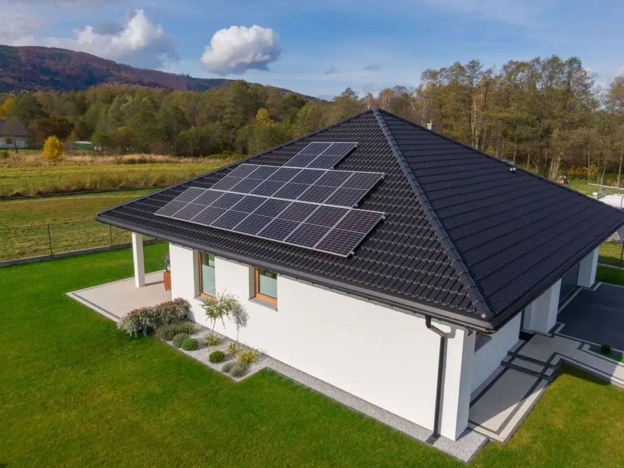 Nowoczesny dom z panelami fotowoltaicznymi na dachu. Credit Agricole kredyt na fotowoltaikę pomoże Ci w inwestycji w zieloną energię.